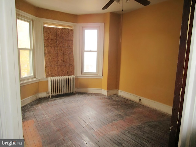 unfurnished room with hardwood / wood-style floors, ceiling fan, and radiator heating unit