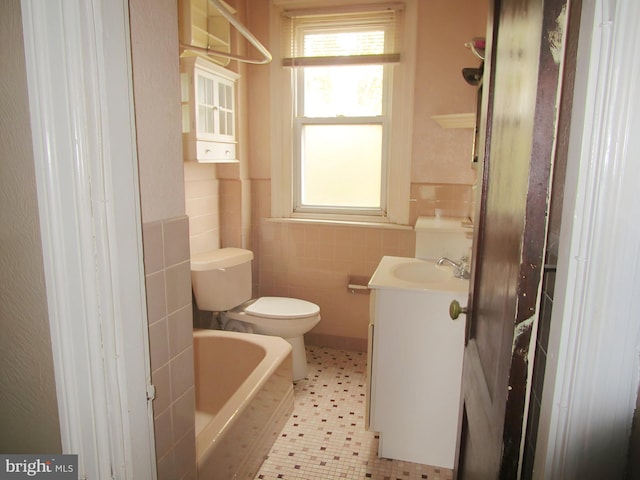 bathroom with tile patterned floors, a tub to relax in, toilet, vanity, and tile walls