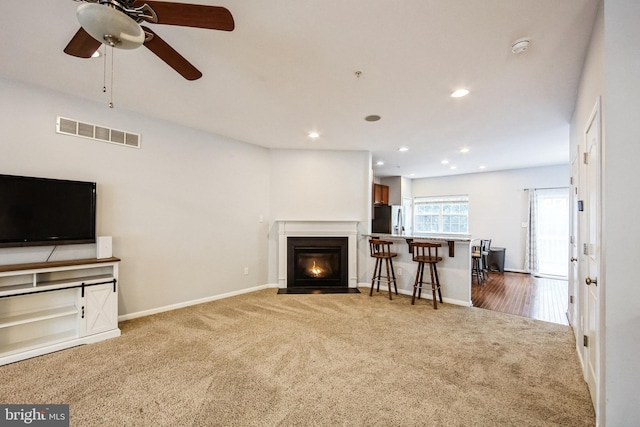 carpeted living room with ceiling fan