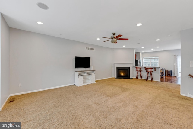 unfurnished living room with ceiling fan and light colored carpet