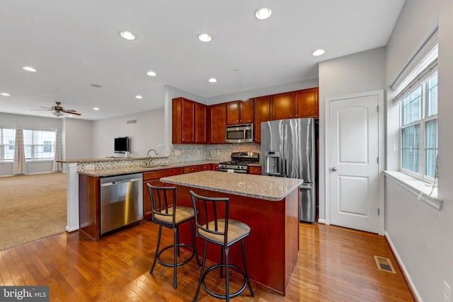 kitchen with a kitchen bar, kitchen peninsula, a wealth of natural light, and stainless steel appliances