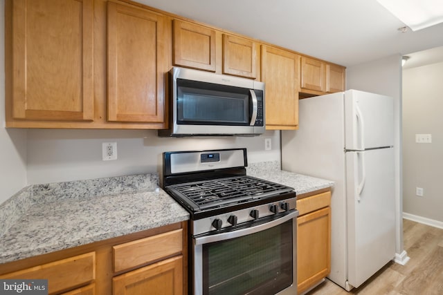 kitchen with light stone counters, light hardwood / wood-style flooring, and stainless steel appliances