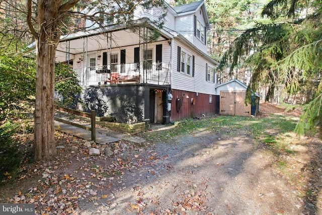 view of home's exterior with a porch and a storage unit