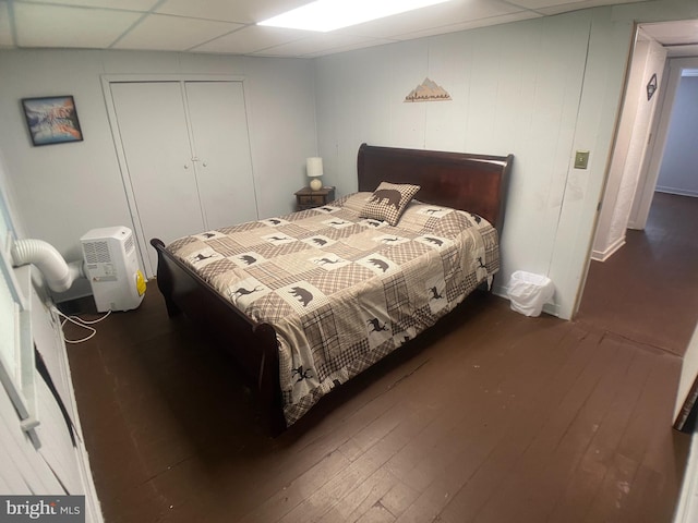 bedroom featuring a paneled ceiling, dark hardwood / wood-style flooring, and a closet