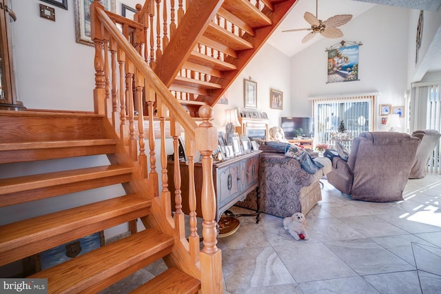 stairs with ceiling fan and high vaulted ceiling