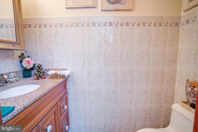 bathroom featuring vanity, tile walls, and toilet