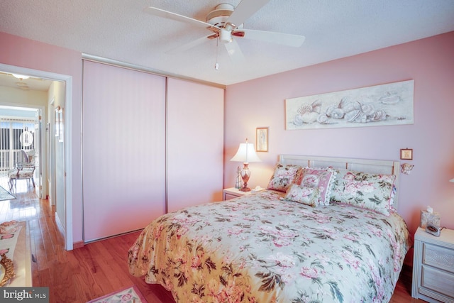 bedroom featuring a textured ceiling, light hardwood / wood-style flooring, a closet, and ceiling fan