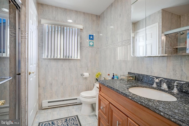 bathroom with tile patterned flooring, a baseboard heating unit, toilet, vanity, and tile walls