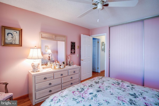 bedroom with a textured ceiling, light hardwood / wood-style flooring, and ceiling fan