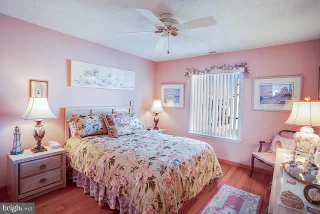 bedroom featuring a textured ceiling, light wood-type flooring, and ceiling fan