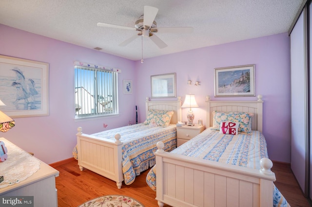 bedroom with ceiling fan, light hardwood / wood-style floors, and a textured ceiling