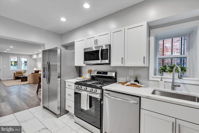 kitchen with white cabinets, stainless steel appliances, a wealth of natural light, and sink