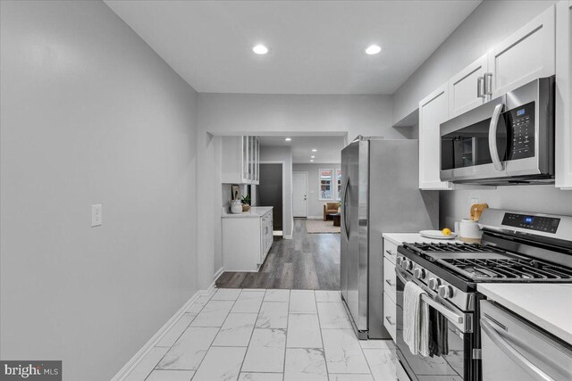 kitchen featuring appliances with stainless steel finishes, light wood-type flooring, and white cabinetry