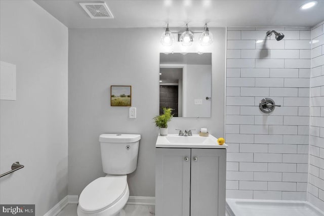 bathroom featuring a tile shower, vanity, and toilet