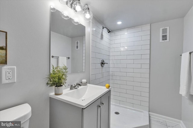 bathroom featuring vanity, toilet, and tiled shower