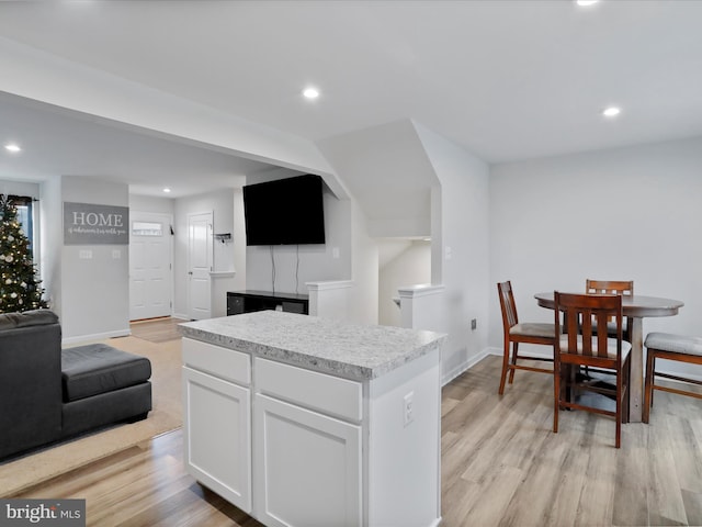 kitchen with light wood-type flooring, a center island, and white cabinetry