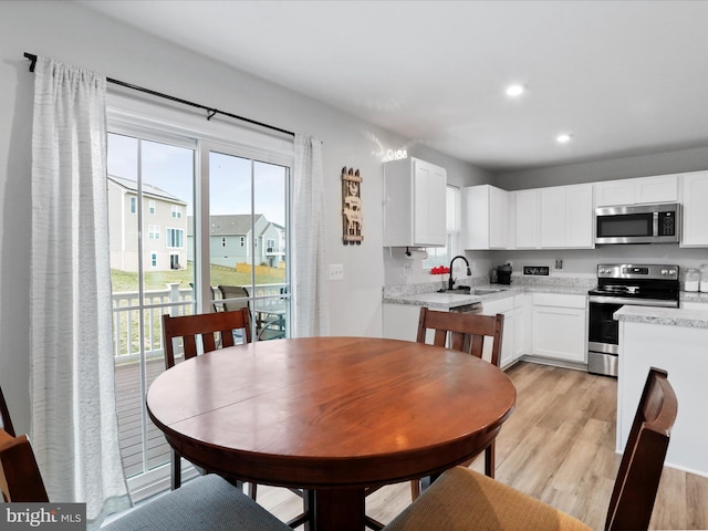 kitchen with white cabinets, appliances with stainless steel finishes, light wood-type flooring, and a healthy amount of sunlight