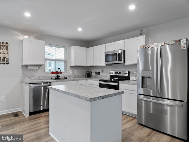 kitchen with a kitchen island, light wood-type flooring, sink, and appliances with stainless steel finishes