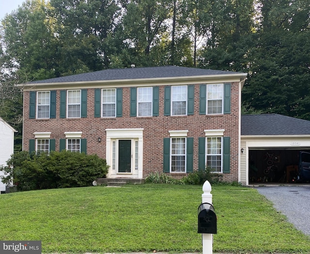 colonial-style house featuring a garage and a front lawn