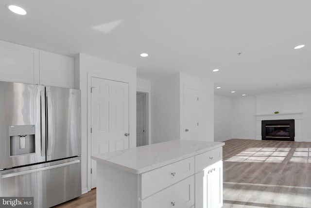 kitchen with white cabinetry, hardwood / wood-style floors, light stone counters, and stainless steel fridge with ice dispenser