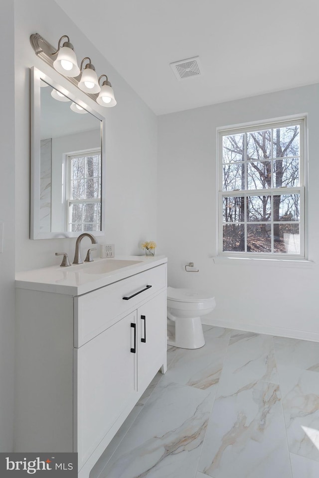 bathroom with plenty of natural light, toilet, and vanity