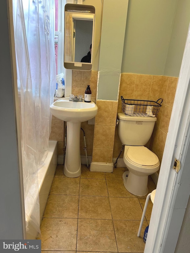 bathroom featuring tile patterned floors, sink, toilet, and tile walls