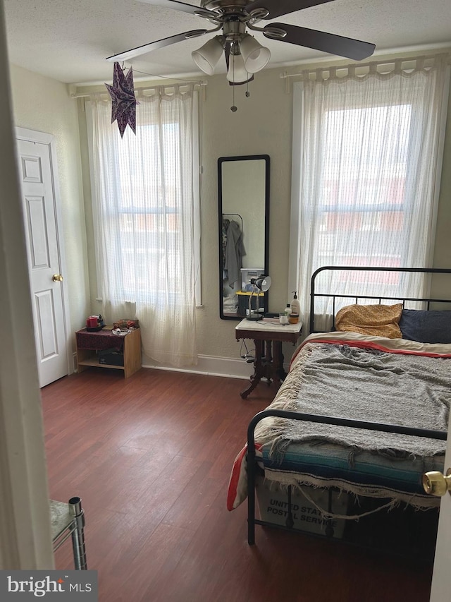 bedroom with wood-type flooring, a textured ceiling, multiple windows, and ceiling fan