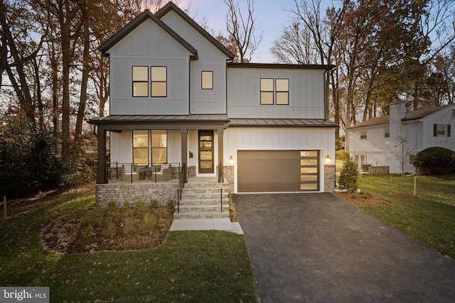 view of front of property featuring a front yard, a porch, and a garage