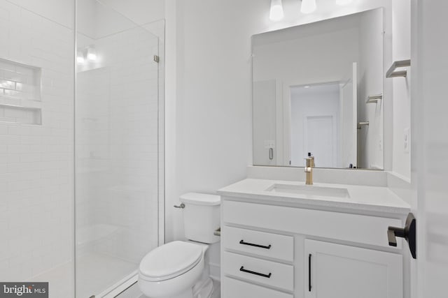 bathroom with a tile shower, vanity, and toilet