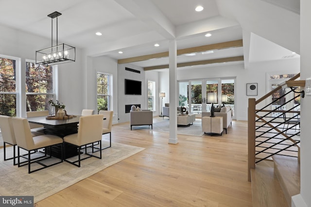 dining space featuring a large fireplace, light hardwood / wood-style flooring, and plenty of natural light