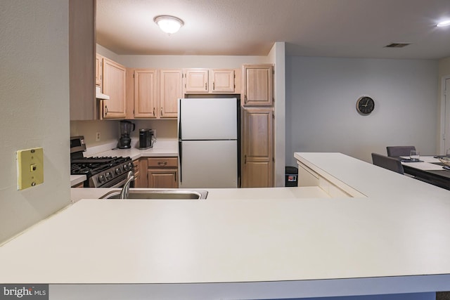 kitchen with light brown cabinetry, extractor fan, stainless steel range with gas cooktop, and white fridge