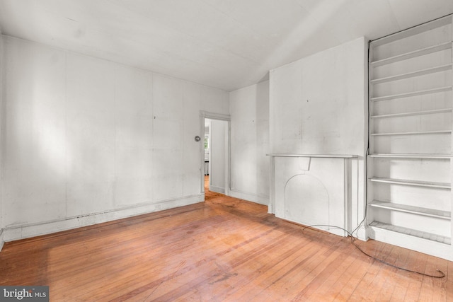 unfurnished room with wood-type flooring and built in shelves