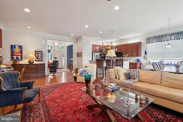 living room with a healthy amount of sunlight, ornamental molding, wood-type flooring, and decorative columns