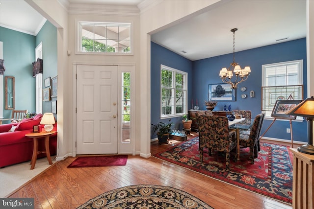 entryway with wood-type flooring, crown molding, and a chandelier