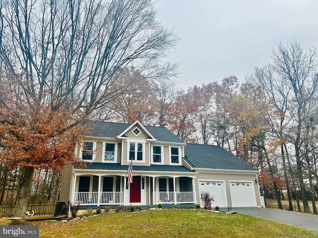 view of front of house with covered porch, a garage, and a front yard