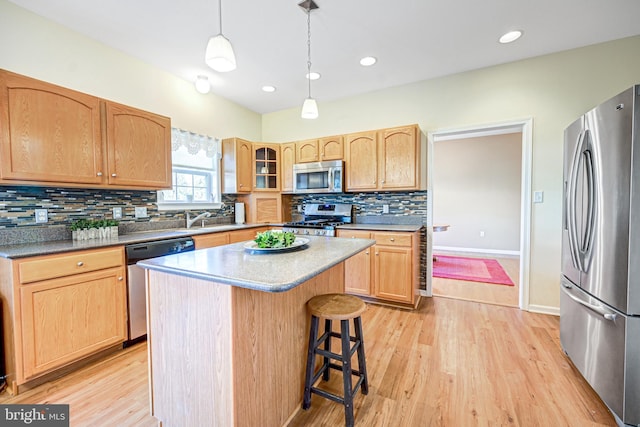 kitchen featuring pendant lighting, light hardwood / wood-style flooring, appliances with stainless steel finishes, tasteful backsplash, and a kitchen island