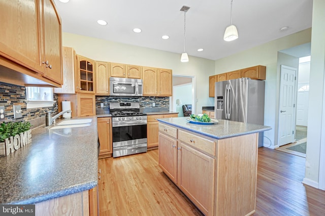 kitchen with light wood-type flooring, appliances with stainless steel finishes, a center island, and sink