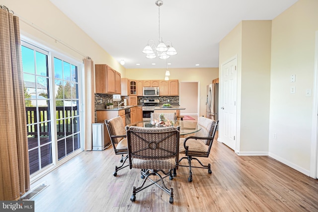 dining space with a notable chandelier, light hardwood / wood-style floors, and sink