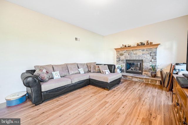 living room featuring a stone fireplace and hardwood / wood-style flooring