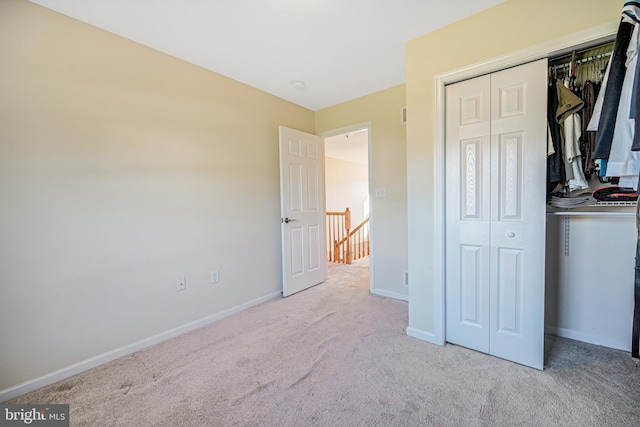 unfurnished bedroom with light carpet and a closet