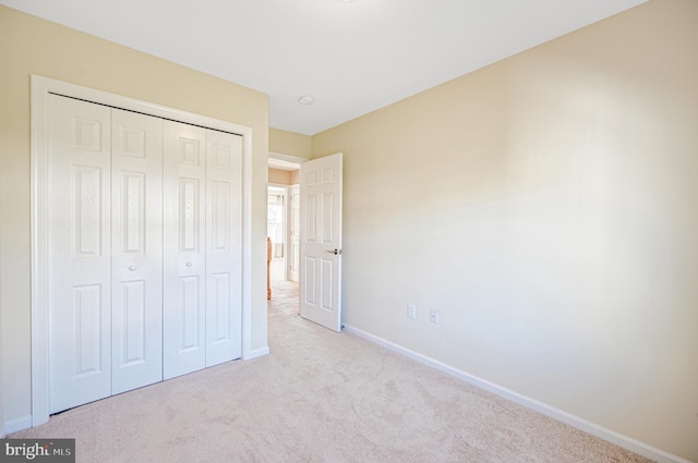 unfurnished bedroom with light carpet and a closet