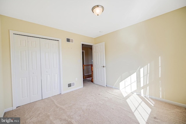 unfurnished bedroom featuring light carpet and a closet