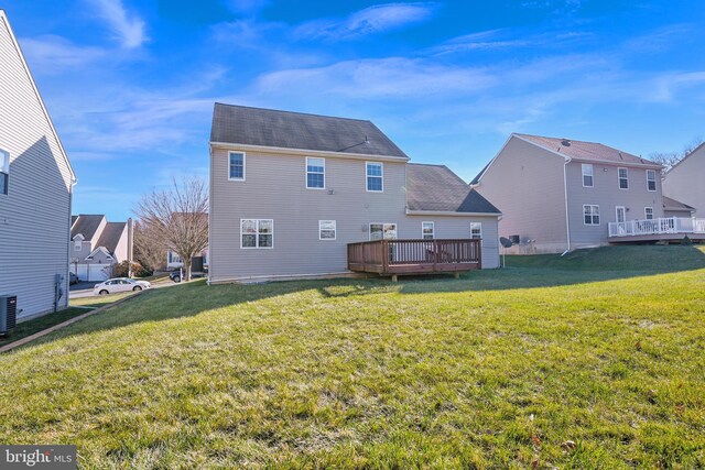 rear view of house with a deck, cooling unit, and a lawn