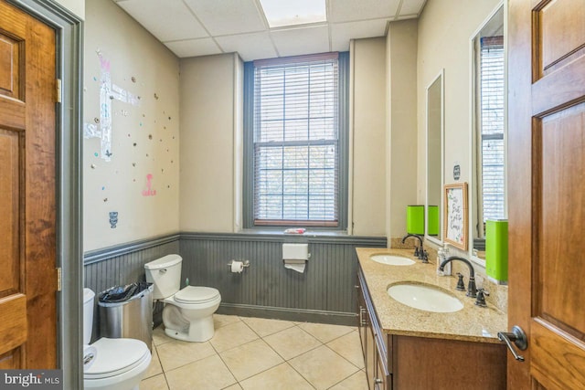 bathroom with tile patterned floors, a drop ceiling, toilet, and vanity