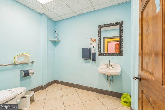 bathroom featuring a paneled ceiling, tile patterned flooring, toilet, and sink