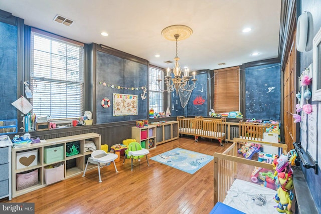 playroom with wood-type flooring and a notable chandelier