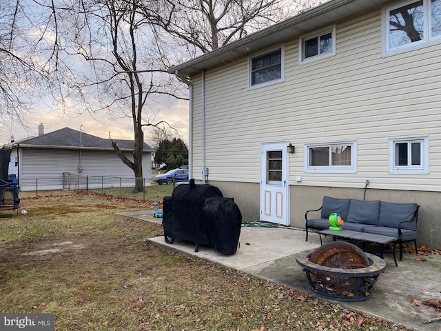 back house at dusk featuring an outdoor living space with a fire pit and a patio