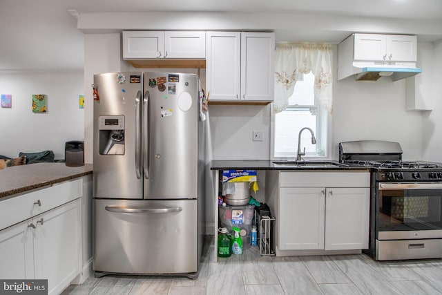 kitchen featuring stainless steel appliances, white cabinetry, dark stone countertops, and sink