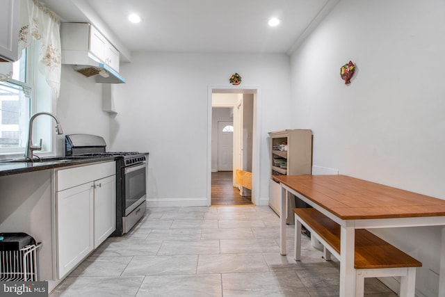 kitchen with stainless steel range with gas cooktop, sink, white cabinets, and light hardwood / wood-style floors