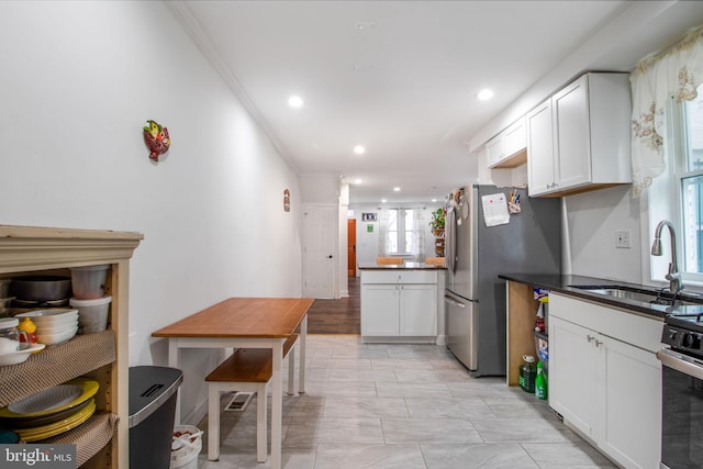 kitchen with white cabinetry, sink, ornamental molding, and appliances with stainless steel finishes